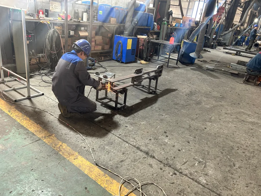 Welder grinding a steel seam with sparks at the JH Amusement ride factory welding bay