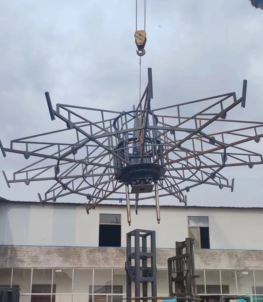 Overhead crane hoisting a star-shaped steel ride frame during assembly at JH Amusement